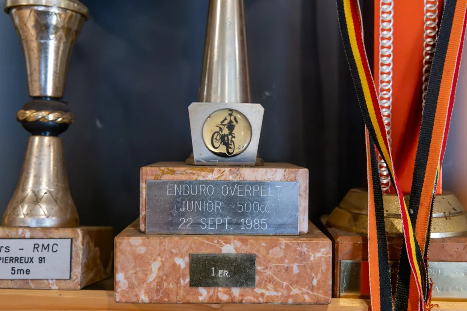 Gros plan sur des trophées et des médailles, dont une coupe d’enduro datée de 1985.