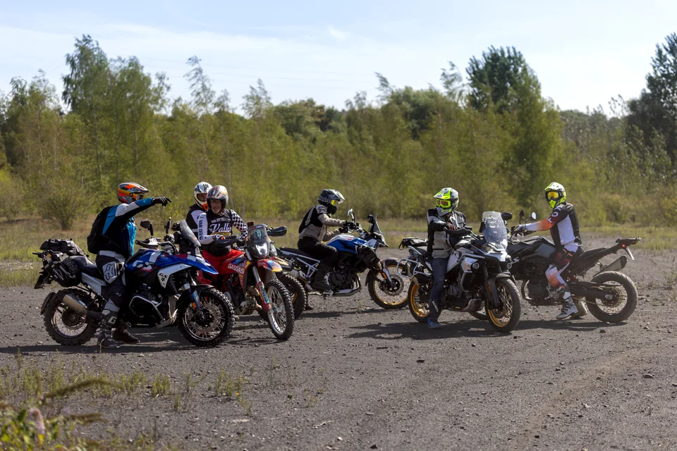 Un groupe de pilotes et leurs motos sont réunis sur une aire dégagée.