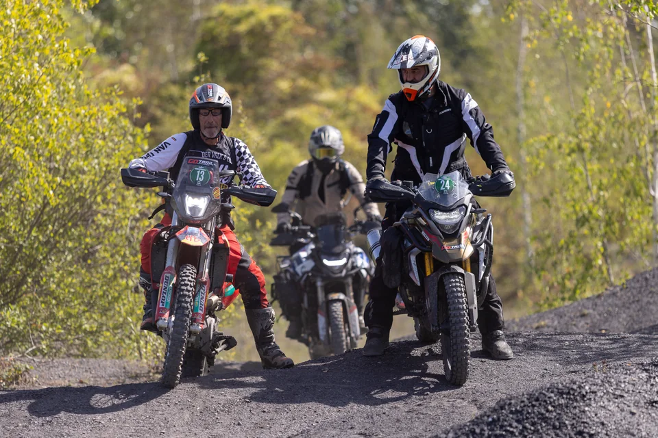 Plusieurs pilotes sont regroupés sur leurs motos au sommet d’une bosse.