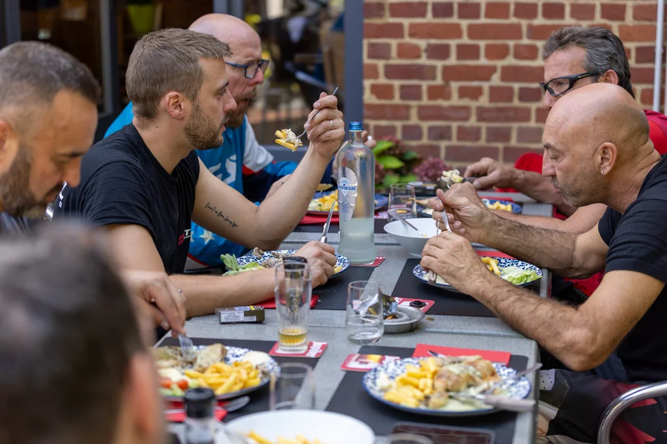 Des participants mangent et discutent autour d’une table à l’extérieur.