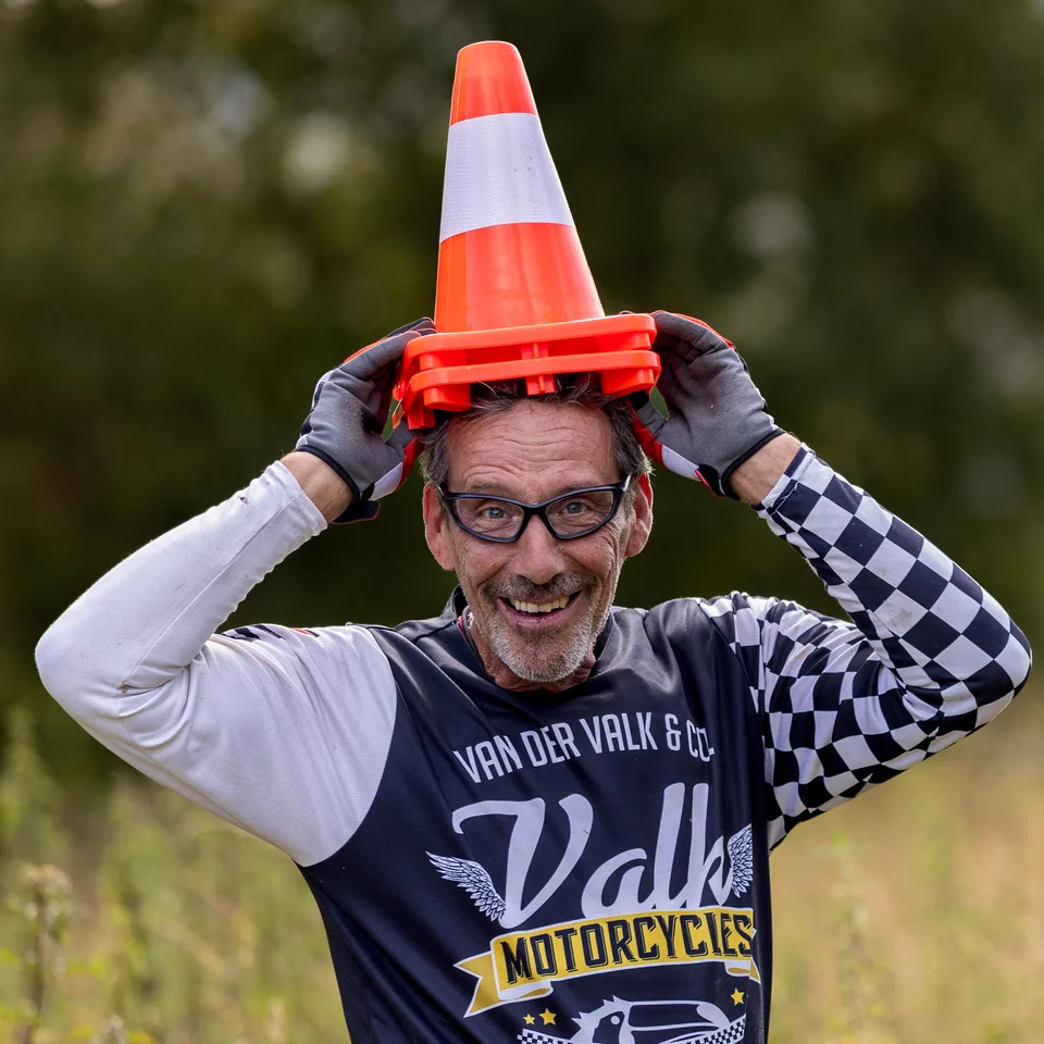Olivier sourit en tenant un cône de signalisation sur sa tête.